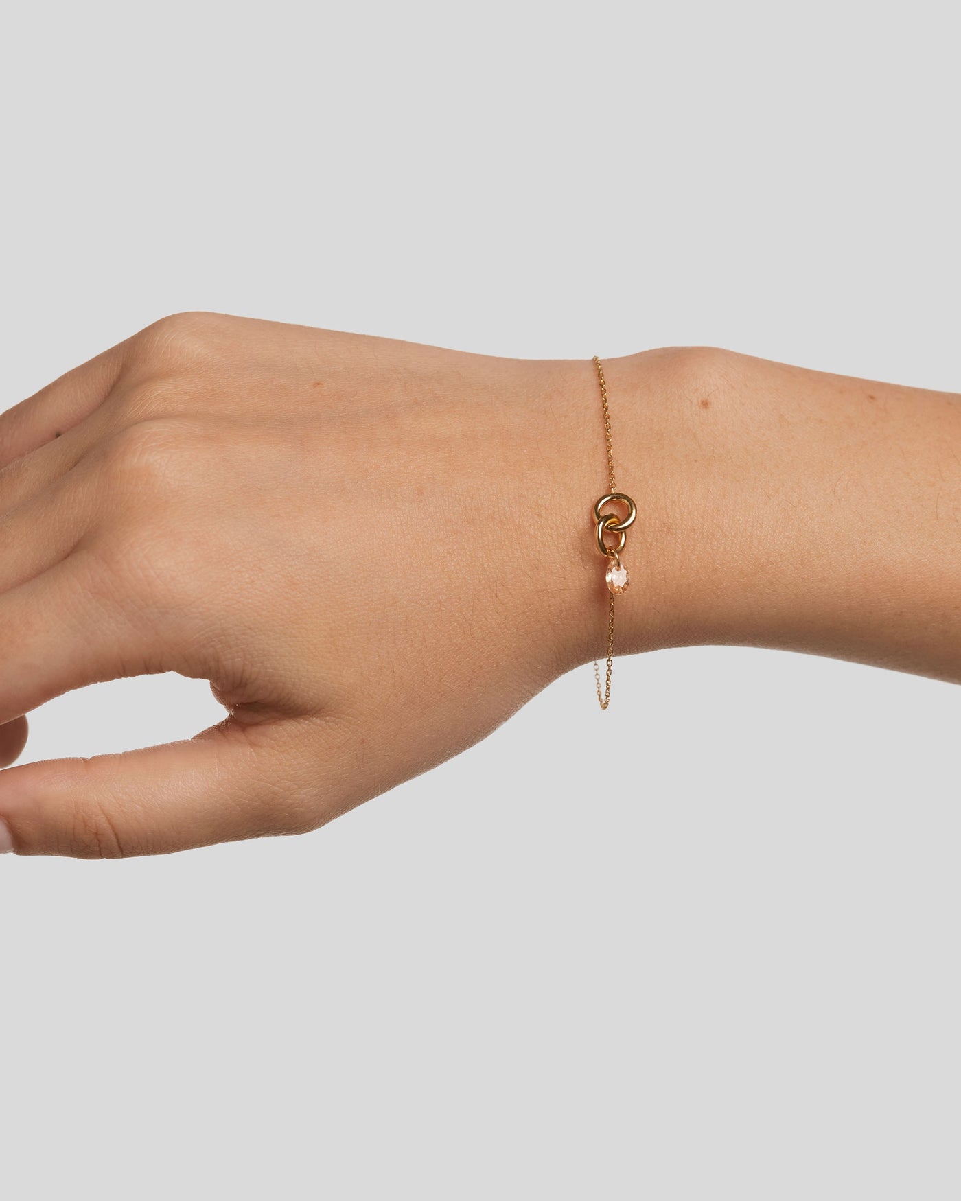 Gold-plated bracelet featuring two interlinked rings with a peach 