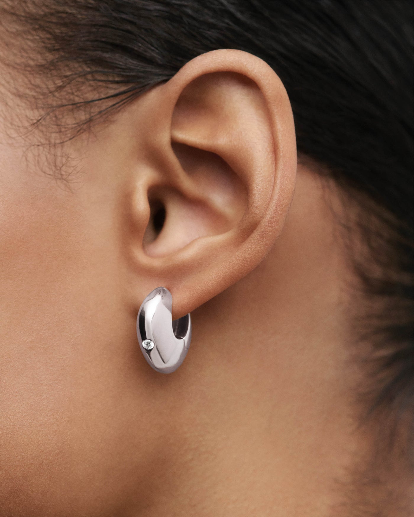 Sculptural silver hoop earrings with asymmetric design adorned