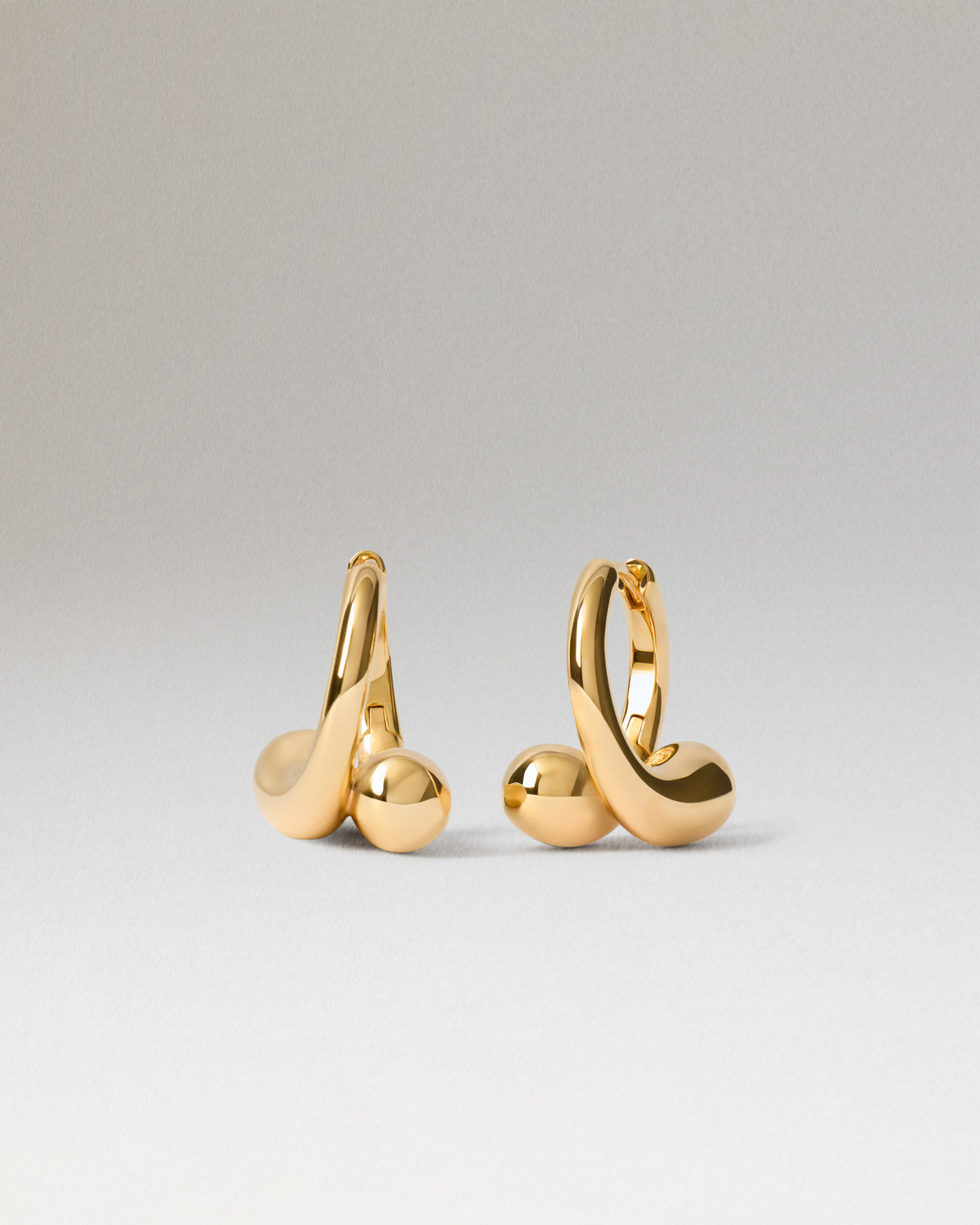 Modern huggie earrings with asymmetric design featuring two overlapping drop-shaped motifs
