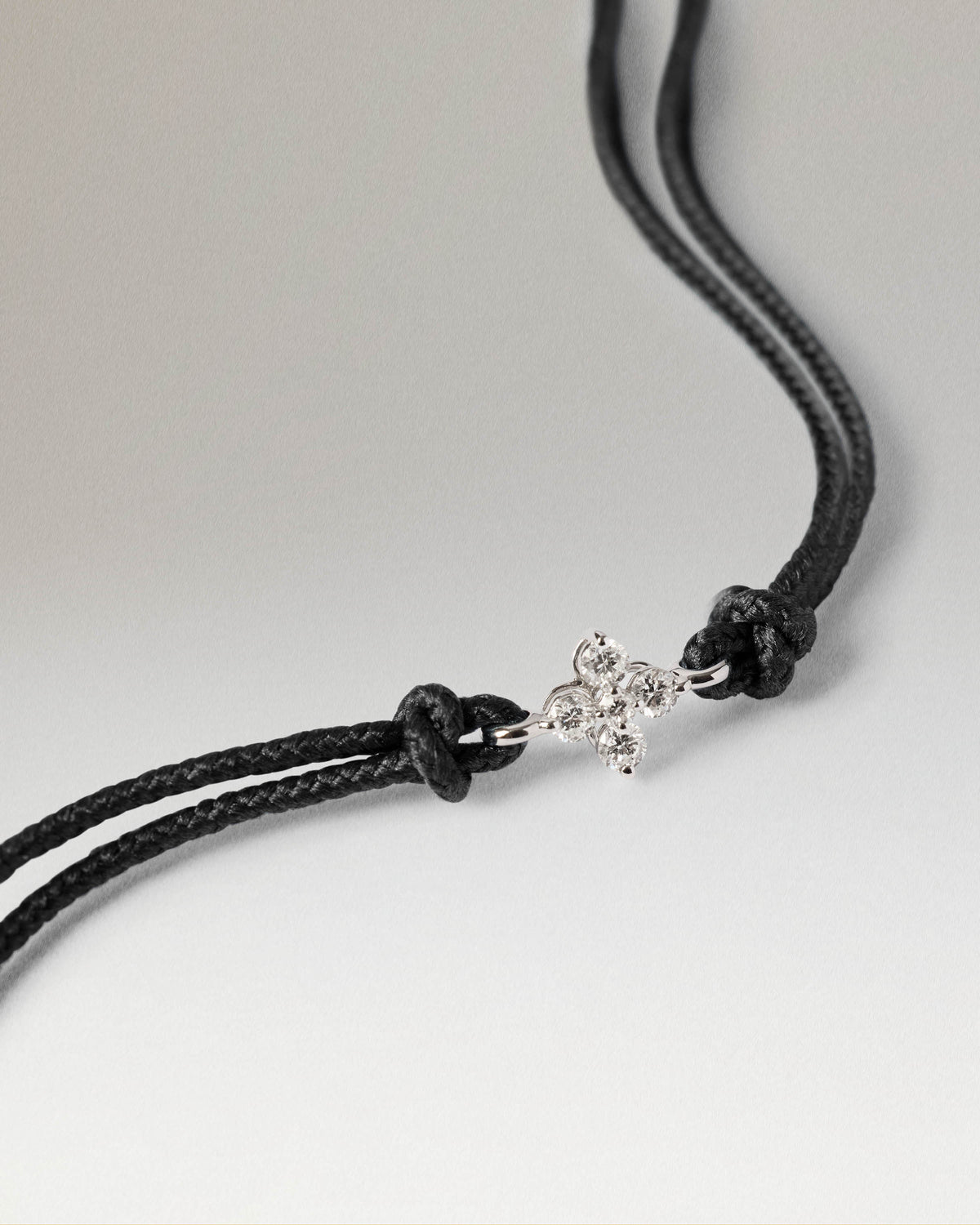 Black cord bracelet featuring a white gold flower set with lab-grown diamonds.