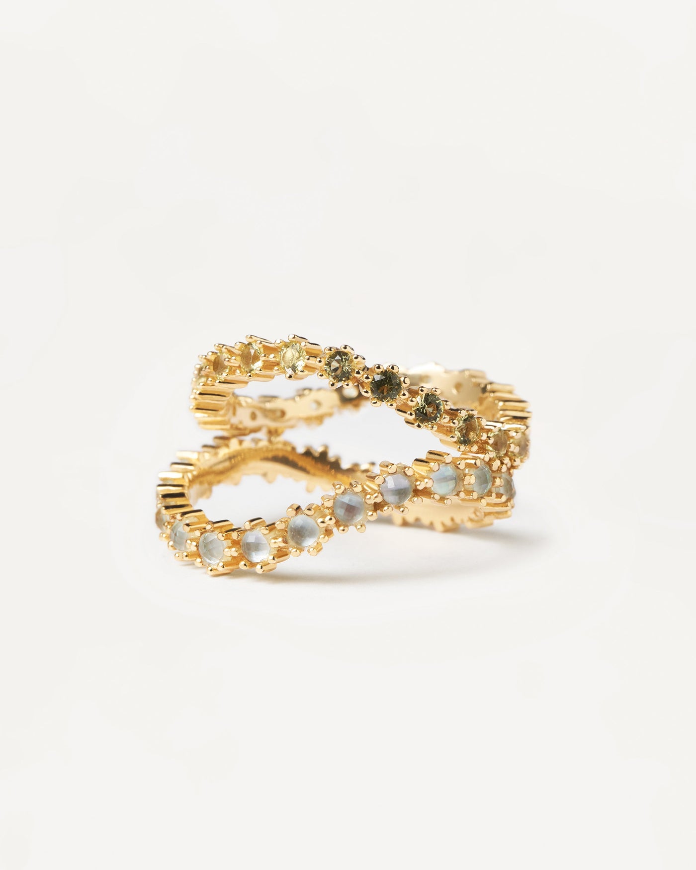 2 wavy eternity rings: one set with light blue zirconia & the other with green zirconia