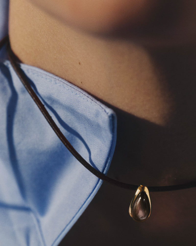 Cord necklace with a brown teardrop stone pendant.
